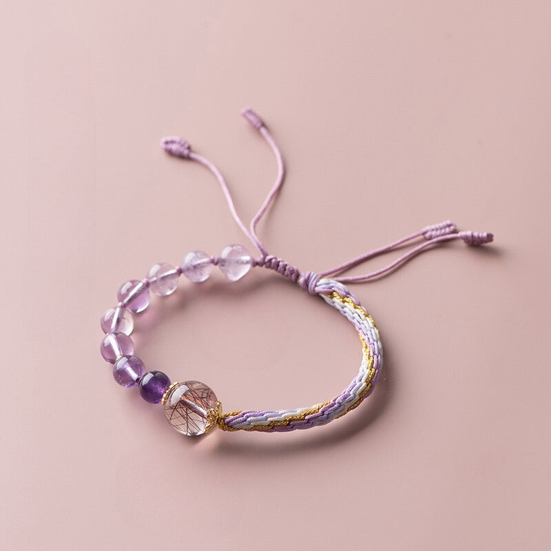 Adjustable bracelet featuring amethyst and rutilated quartz beads, designed for spiritual healing and mental clarity.