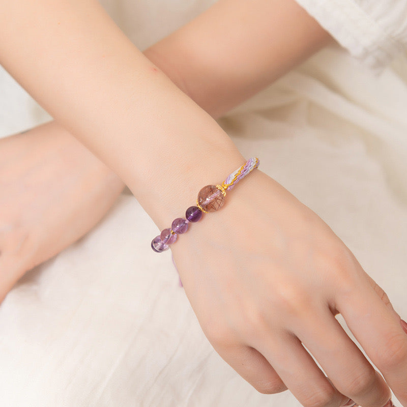 Adjustable bracelet featuring amethyst and rutilated quartz beads, designed for spiritual healing and mental clarity.