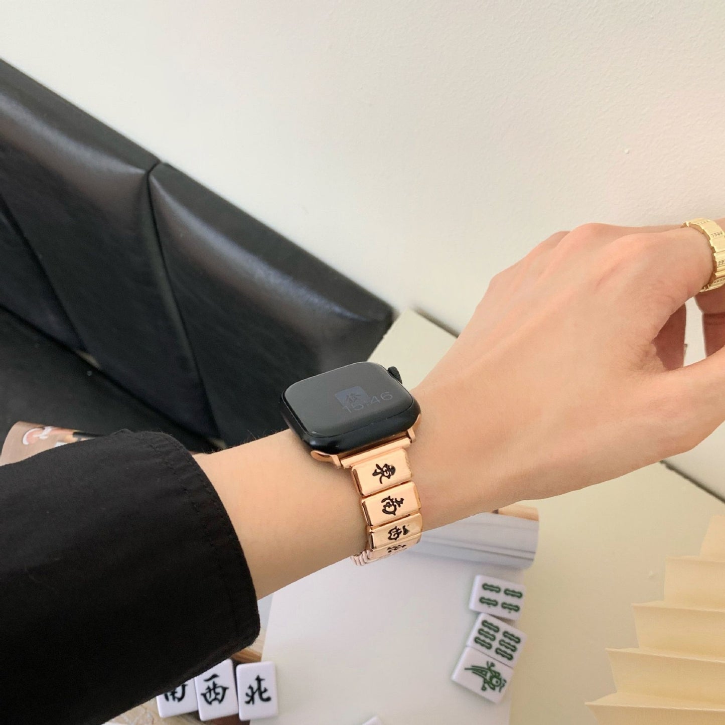 Rose gold Mahjong Apple Watch band displayed on a wrist, with traditional Mahjong tiles in the background.