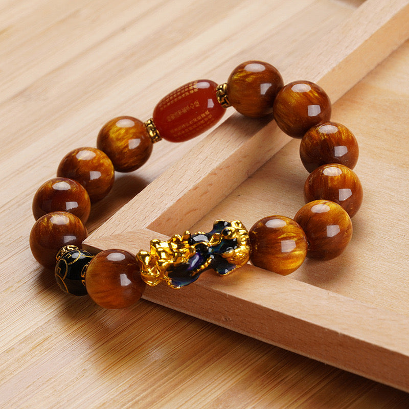 Rich brown Tiger’s Eye beads with a golden Pi Xiu charm, believed to attract wealth and protection.